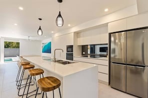 Una cucina moderna con isola centrale, elettrodomestici in acciaio inossidabile e sgabelli da bar in legno.