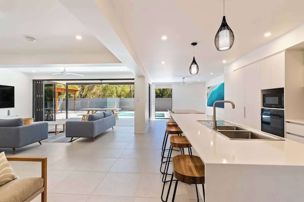 Una cucina moderna con un'area bar, un angolo salotto con divani e un'ampia finestra.