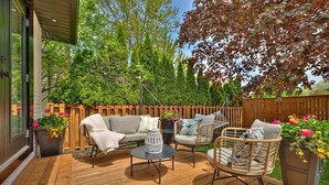 Une terrasse en bois avec un canapé, deux chaises et une table.