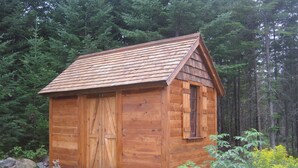 A wooden cabin with a gabled roof, large wooden doors, and a window. - Welcome to Valhalla (Rangeley)