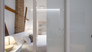 A bedroom with a bed, bedside table, lamp, and a brick wall. - ChezmoiHomes Patio Zahorí 4 (Granada)