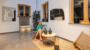 A spacious room with a stone fountain, a large potted plant, and a round wooden table with two bottles. - ChezmoiHomes Patio Zahorí 4 (Granada)