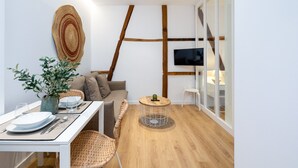 A modern living room with a dining area, a large woven rug, a television, and a wooden floor. - ChezmoiHomes Patio Zahorí 4 (Granada)