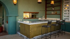 A bar area with a counter, stools, and hanging lights.