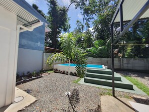 A swimming pool with steps leading up to it, surrounded by a gravel area and some plants. - Casa BRUJA (Cahuita)