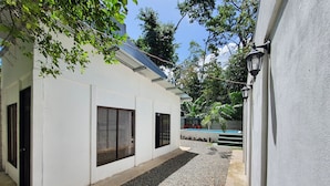A white building with a pool, gravel pathway, and trees. - Casa BRUJA (Cahuita)