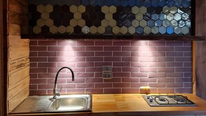 A kitchen with a hexagonal tile backsplash, a stainless steel sink, and a gas stove.