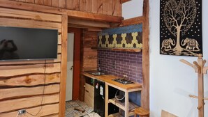 A rustic kitchen with wooden beams, a tiled backsplash, a built-in stove, and a wooden coat rack.