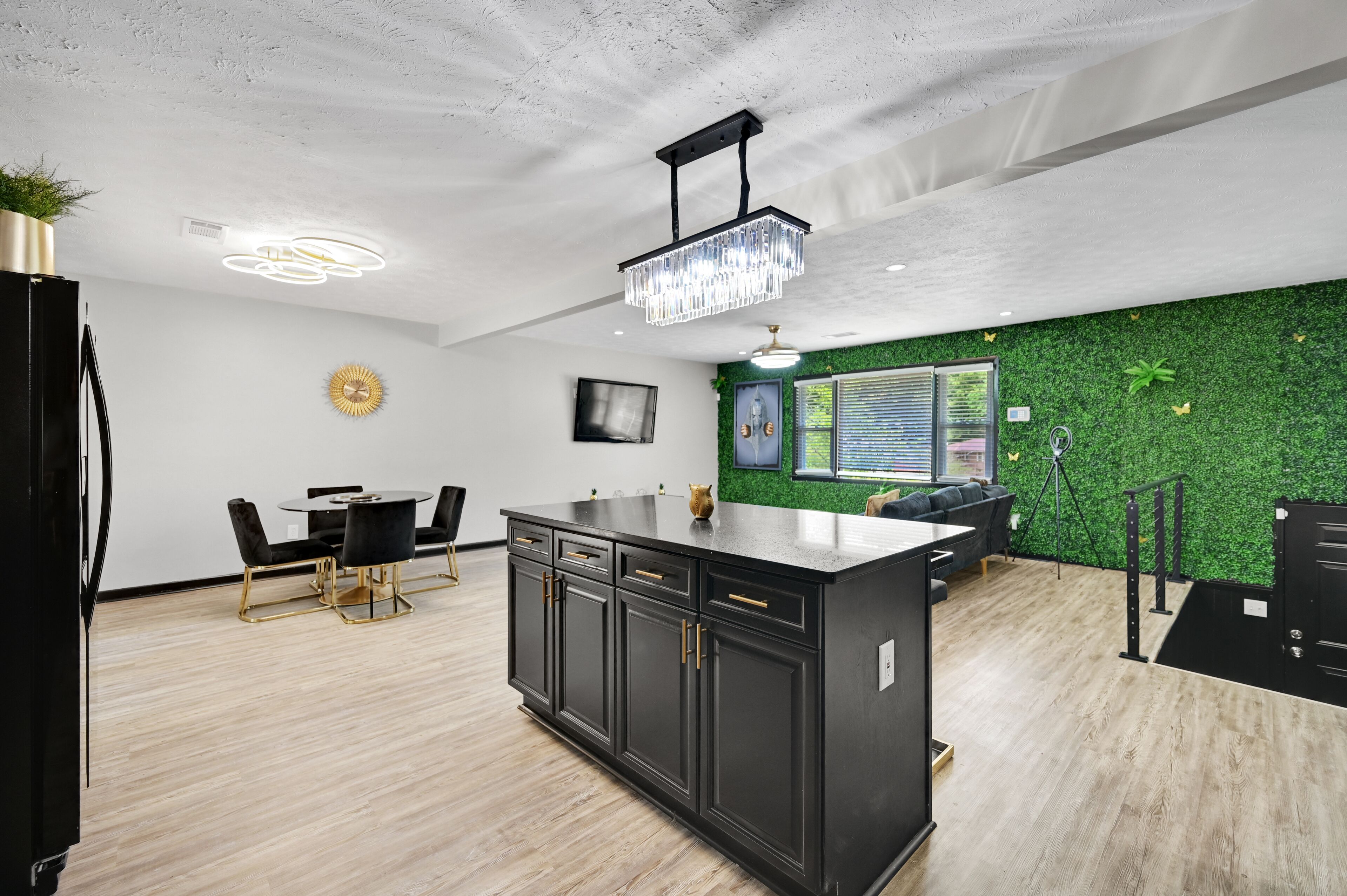 Una cocina moderna con una isla negra, techo blanco y detalles de pared verdes.
