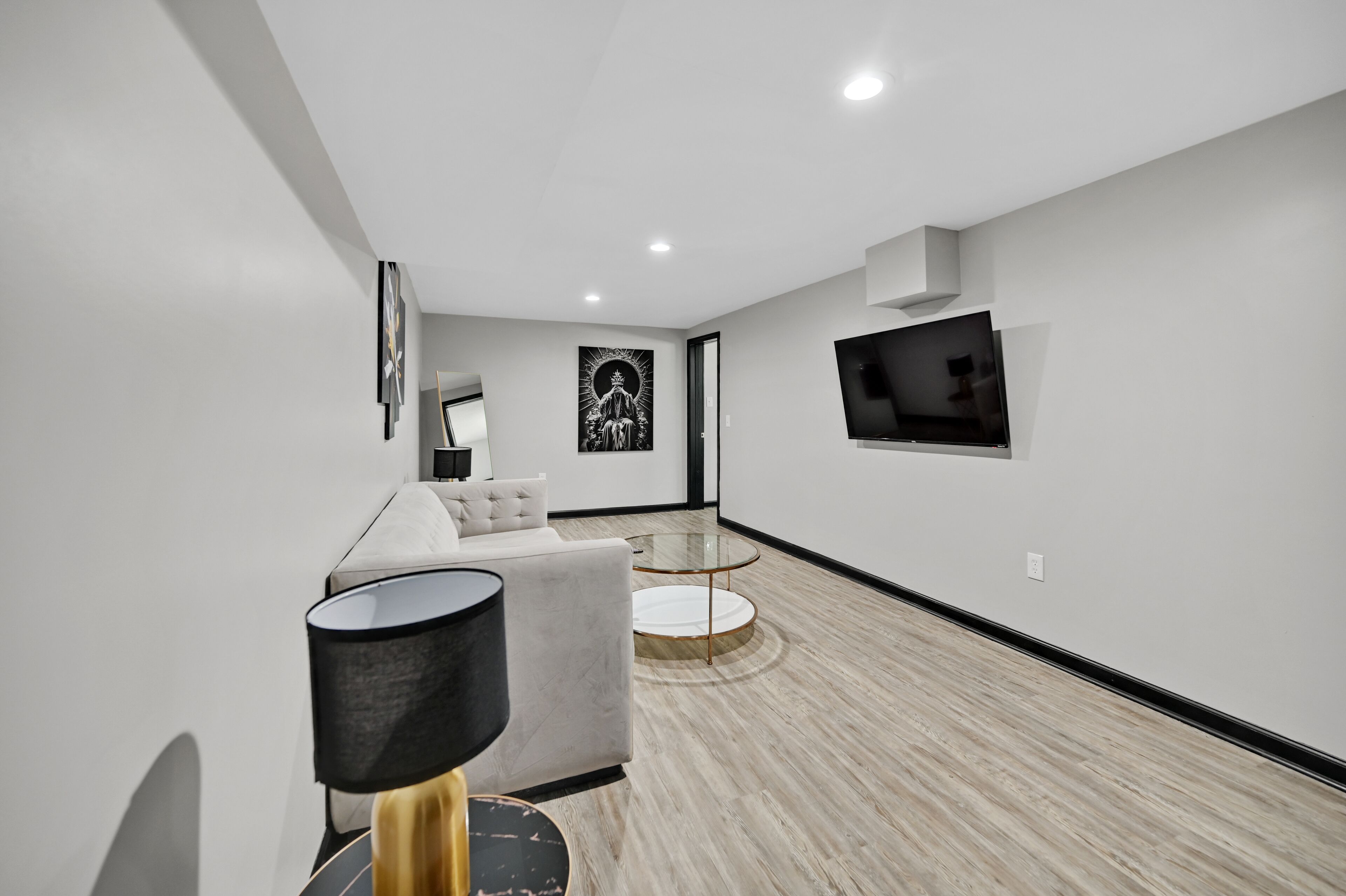 A modern living room with a grey sofa, a round coffee table, and a TV mounted on the wall.
