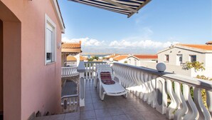 A balcony with a white railing, a white lounge chair, and a view of the sea and buildings. - Amazing apartment in Vir with WiFi (Vir)