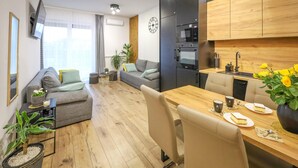 Ein modernes Wohnzimmer mit einem Holzesstisch, einer Couch und einer Küchenzeile, inklusive Mikrowelle und Ofen.