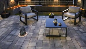 Eine Terrassenausstattung mit zwei grauen Sesseln, einem schwarzen Couchtisch und einem kleinen Vogelkäfig.