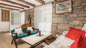 Una stanza rustica con pareti in pietra, travi di legno e un tavolo con una candela rossa.