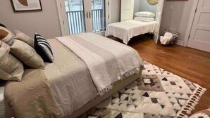 Um quarto com uma cama, um tapete e uma porta que dá para outro cômodo.