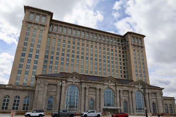 A large, multi-story building with a classical architectural style, featuring a central entrance with large arched windows and a symmetrical facade.