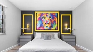 A modern bedroom with a large bed, grey walls, and a vibrant lion painting on the wall.