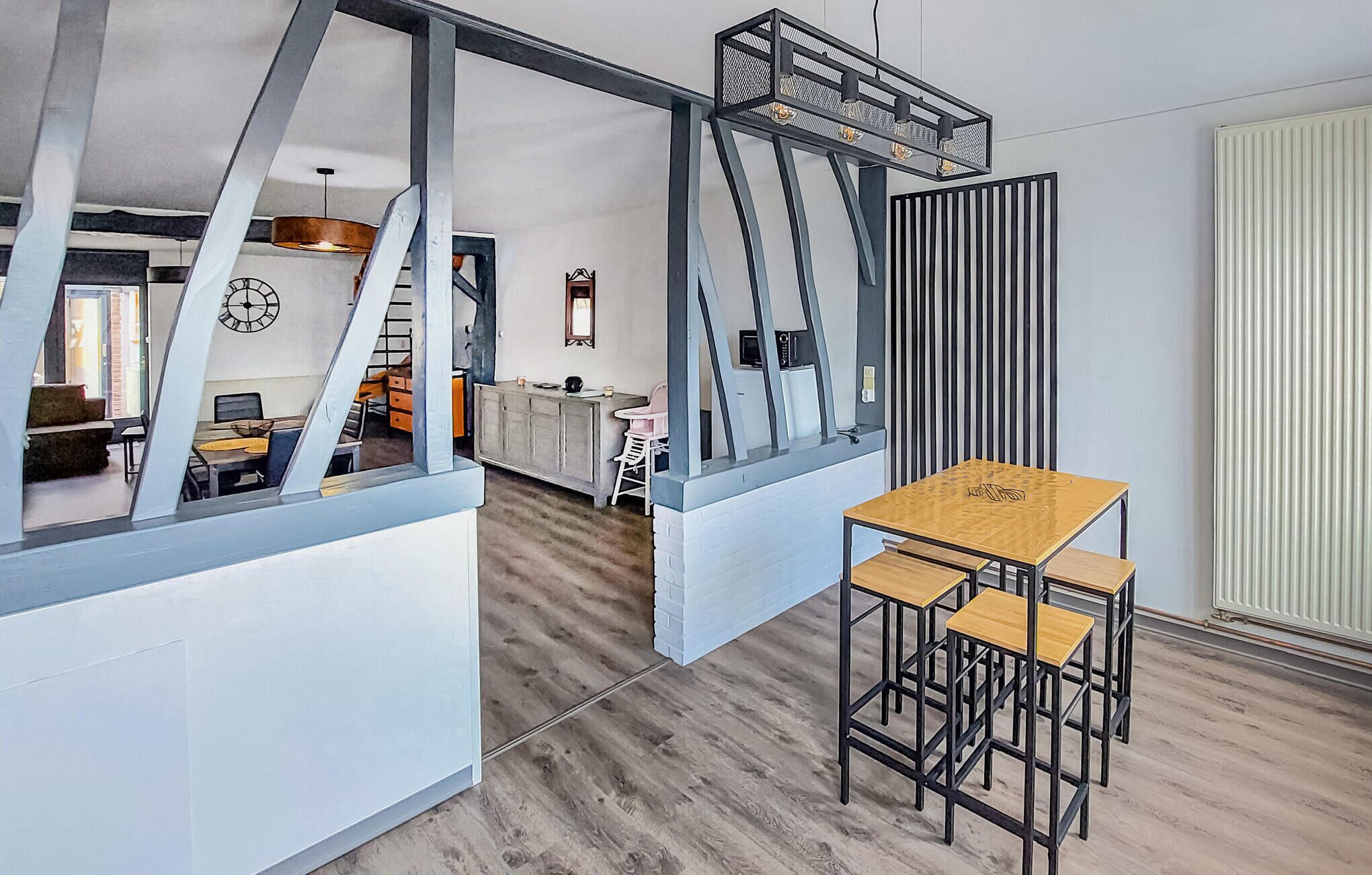 Una cocina moderna con una isla central, un comedor con mesa y sillas de madera, y vistas del espacio de estar contiguo.