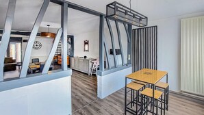 Eine moderne Küche mit Kochinsel, ein Essbereich mit Holztisch und Stühlen sowie Blick auf den angrenzenden Wohnraum.