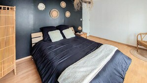 Ein Schlafzimmer mit Bett, Nachttisch, Lampe und einer hängenden Leuchte mit Gewebekäfig.