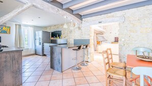 Una cocina amplia con una isla central, un comedor con sillas y una pared de piedra.