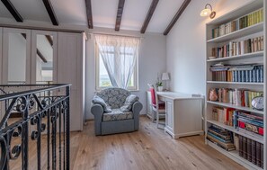 Relax in a cozy room with a comfortable armchair, desk, and bookshelf.