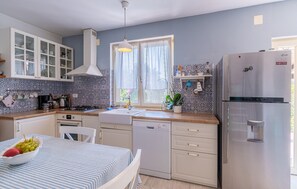 Modern kitchen with stainless steel appliances, white cabinetry, and a tiled backsplash.