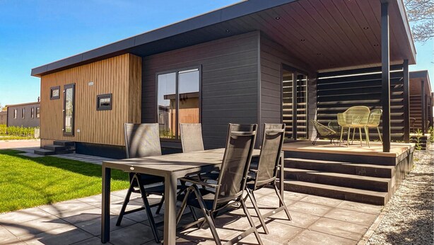Ein modernes Haus mit einer Terrassenanlage, komplett mit Tisch und Stühlen.