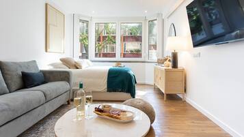 Ein modernes Schlafzimmer mit einem Bett, einem Sofa, einem Fernseher und einem Esstisch mit Speisen und Getränken.