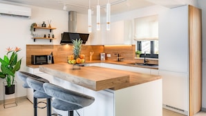 A modern kitchen with a wooden island, white cabinetry, and a built-in microwave. - Stunning home in Blato (Blato)