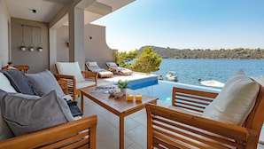 A modern outdoor seating area with wooden furniture and a pool overlooking a lake. - Stunning home in Blato (Blato)