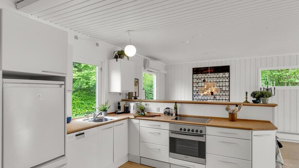 Une cuisine moderne avec des meubles blancs, un plan de travail en bois et un four encastré.