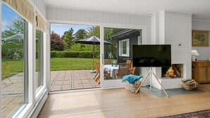Un salon moderne doté d’une cheminée, d’un téléviseur et d’un espace patio aménagé avec du mobilier d’extérieur.