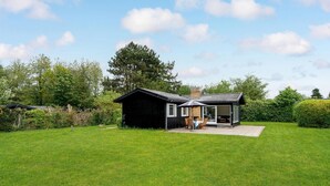Une maison moderne dotée d’une grande pelouse, d’une terrasse avec mobilier d’extérieur et d’un garage.