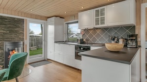 A modern kitchen with white cabinets, a black countertop, and a stone backsplash.