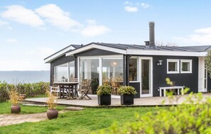 Ein modernes Haus mit Terrasse, großen Fenstern und Meerblick.