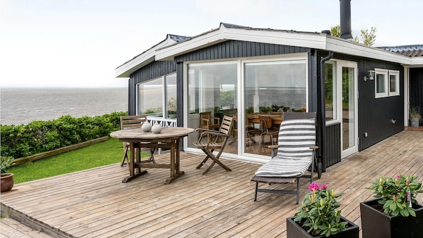 A modern house with a deck, a table, chairs, and a view of the sea. - Lovely home in Esbjerg V with house sea view (Esbjerg V)