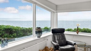 A room with a view of the sea, a black leather chair, a small table, and a lamp. - Lovely home in Esbjerg V with house sea view (Esbjerg V)