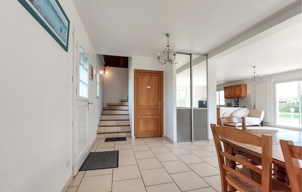 A modern kitchen with wooden cabinets, a dining area with a table and chairs, a staircase leading to another level, and a chandelier. - Amazing home in ST PAER with WiFi (ST PAER)