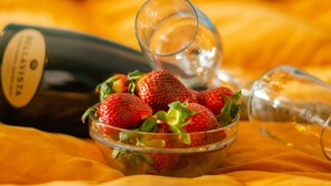 A bowl of strawberries on a table with a wine bottle and a wine glass. - Mantegna - Parzanica (Lombardia)
