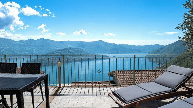 A terrace with a view of mountains and a lake, furnished with a table and two lounge chairs. - Mantegna - Parzanica (Lombardia)