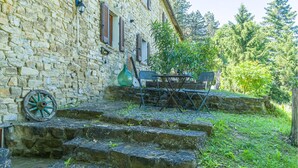 A stone building with a rustic charm, featuring a set of stone steps leading to a small outdoor seating area with a table and chairs. - Awesome apartment in Monastero Bormida with house a panoramic view (Monastero Bormida)