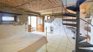 A bedroom with a bed, a staircase, and a stone wall. - Awesome apartment in Monastero Bormida with house a panoramic view (Monastero Bormida)