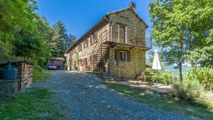 A stone building with a gravel driveway leading to a wooden table and chairs outside. - Awesome apartment in Monastero Bormida with house a panoramic view (Monastero Bormida)
