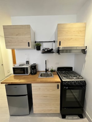 Une cuisine compacte équipée d’un four à micro-ondes, d’une machine à café, d’un évier et d’une cuisinière.