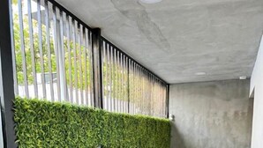 Un área de estar moderna al aire libre con mesas y bancos de madera, un muro vertical con jardín y un techo de hormigón.