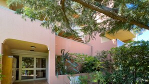 A building with a pink exterior, a tiled entrance, and a garden area with various plants. - LA BADINE Studio AirCo Pool for 2 By Sunset (Antibes)