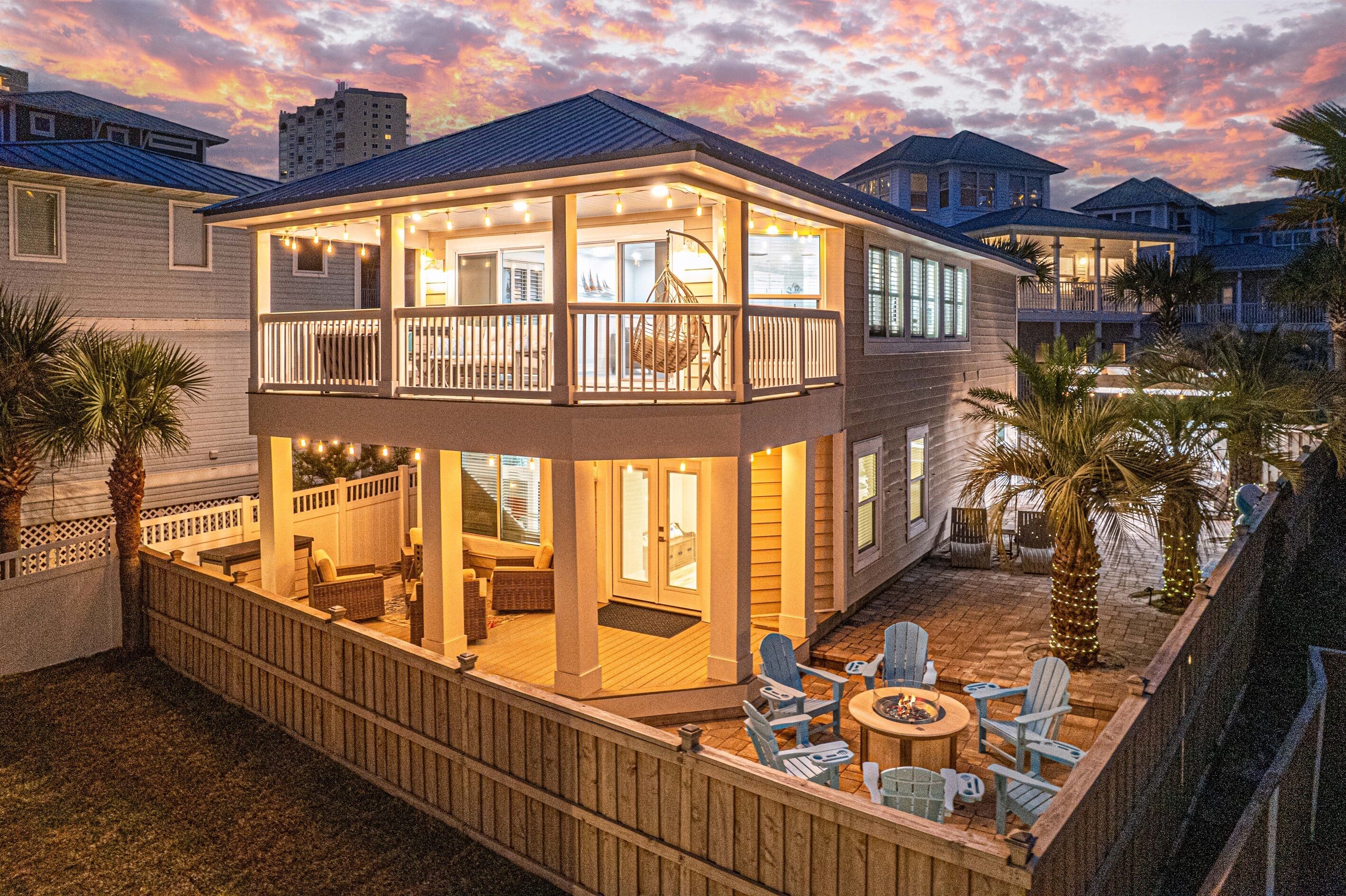 A two-story house with a balcony, outdoor seating, and a fire pit.