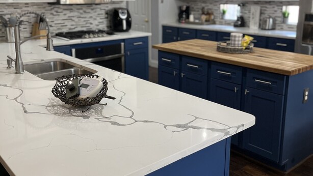 A modern kitchen with white and blue cabinetry, a marble countertop, and a hanging light fixture. - Beautiful Home W/Heated Pool- Sleeps 16, Pets & Small Events Allowed W/Approval  (Mansfield)