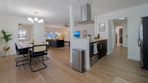 A modern kitchen with a central island, stainless steel appliances, and a dining area with a large table and chairs.